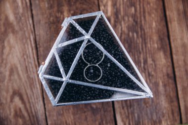 Ahşap masadaki dekoratif kutuda zarif alyansların yakın plan görüntüsü.        