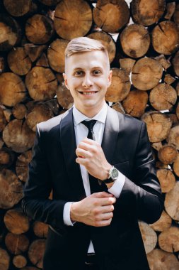 Siyah takım elbiseli ve kravatlı, kameraya gülümseyen yakışıklı bir gencin portresi.