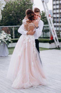 Mutlu gelin ve yakışıklı damat düğün günü sarılıyor.