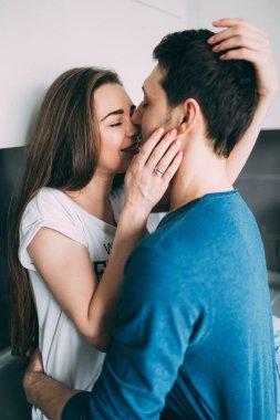Genç çift sabah mutfakta öpüşüyor. 