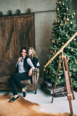 Mutlu anne ve küçük kızı Noel için dekore edilmiş stüdyoda poz veriyorlar.