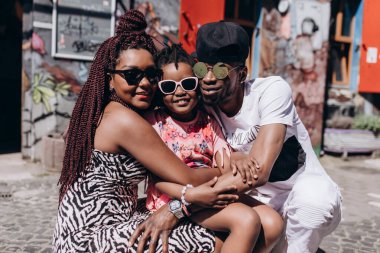 Annesi, babası ve kızıyla sokakta poz veren Afrikalı bir aile.