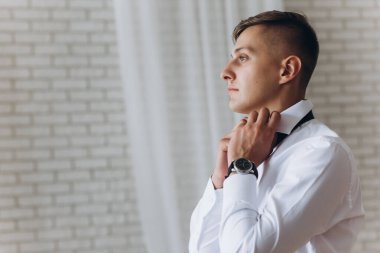 Beyaz gömlekli, siyah kravatlı yakışıklı bir adam.