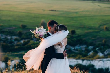 Güzel bir çift gün batımında kırsalda sarılıyor.