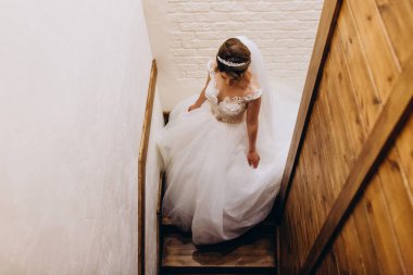 Yüksek açılı beyaz gelinlik içinde merdivenlerden çıkan genç gelinin görüntüsü. 