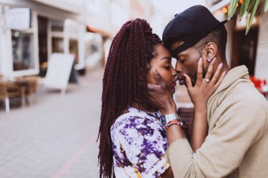 Afrikalı çift sokakta öpüşüyor ve sarılıyor.