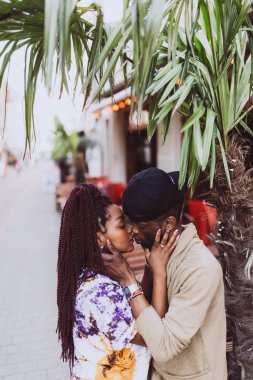 Afrikalı çift sokakta öpüşüyor ve sarılıyor.