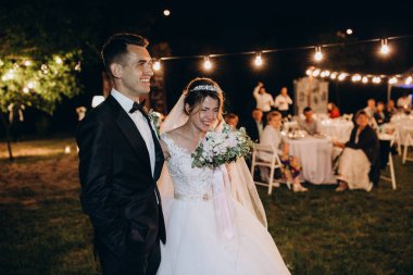 Gelin ve damat gülerek ve dışarıda poz vererek gece