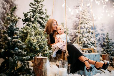 Anne ve kızı salıncaktaki Noel ağacında. 