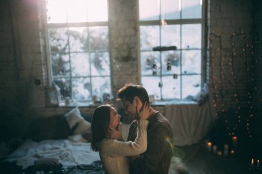 Güzel, mutlu, birbirine aşık genç bir çift sıcak bir odada kucaklaşıyorlar..                   