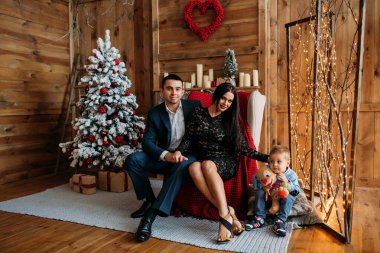 Stüdyoda oğluyla mutlu bir aile Noel ağacı süslemesi yapıyor.