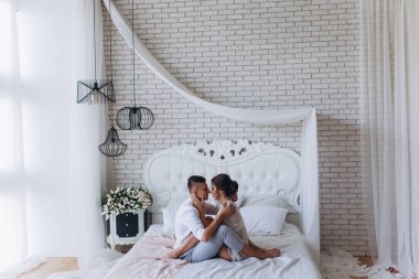 Güzel, genç ve mutlu bir çift yatak odasında birlikte oturuyor.              