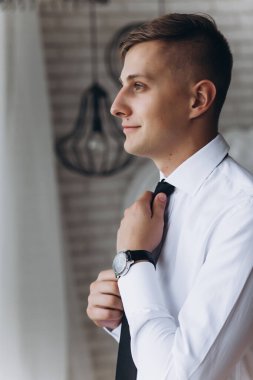 Beyaz gömlek ve siyah kravat takan yakışıklı bir gencin portresi.