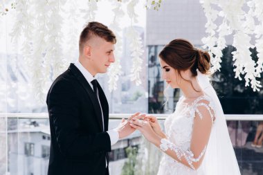 Evlilik töreninde yüzük takan mutlu genç bir çiftin yan görünüşü