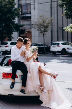 Güzel genç gelin ve damat düğün gününde lüks bir arabada oturuyor.