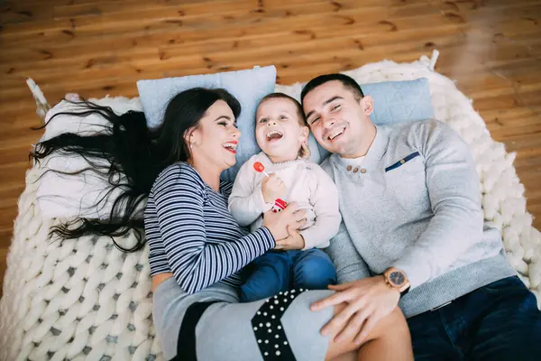 Genç ve mutlu bir aile ve erkek bebek yatakta uzanıyor.