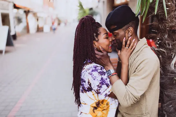 Afrikalı çift sokakta öpüşüyor ve sarılıyor.