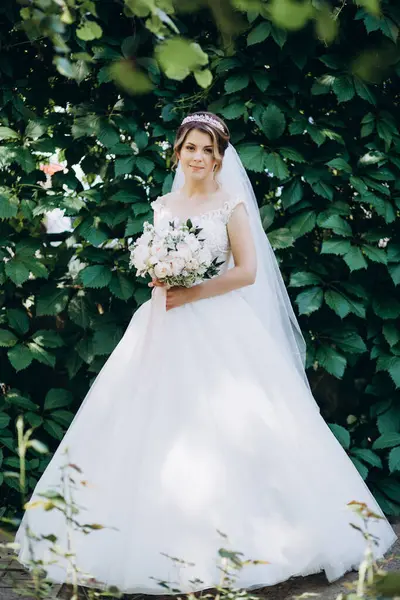 Gelinlikli güzel gelinin portresi Parkta bir buket çiçek tutuyor            