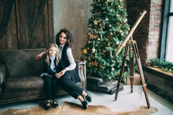 Mutlu anne ve küçük kızı Noel için dekore edilmiş stüdyoda poz veriyorlar.