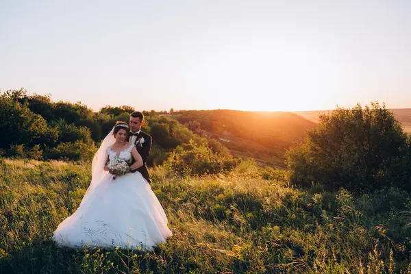 Gelin ve damat çifti düğün günlerinde gün batımında doğada yürüyorlar.         