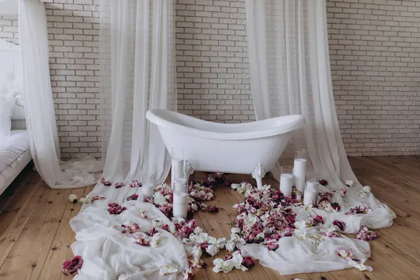 Banyoda çiçekler ve mumlarla dolu güzel beyaz bir küvet.               