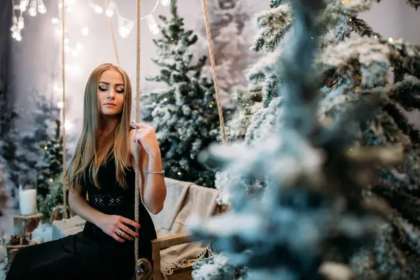 Stüdyodaki kız Noel süsleriyle salıncakta sallanıyor. Yeni yıl arifesi