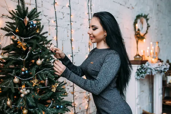 Odada Noel ağacı süsleyen genç ve güzel bir kadın.