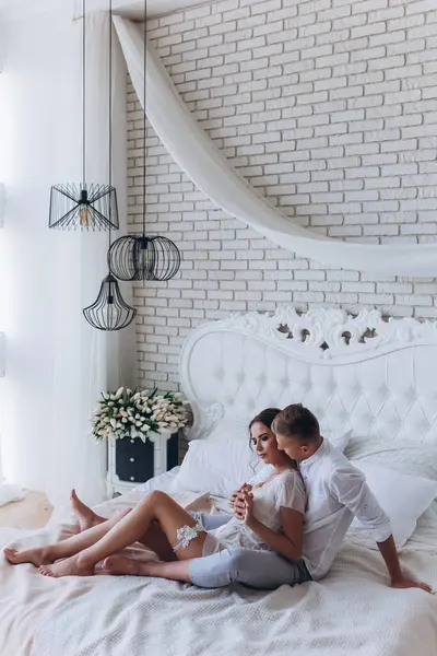 Güzel, genç ve aşık bir çift yatakta sarılıyor.