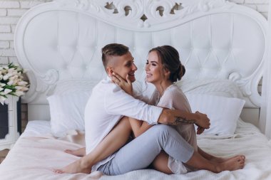 Güzel, genç ve mutlu bir çift yatak odasında birlikte oturuyor.              