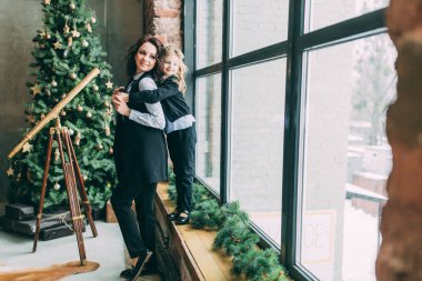 Anne ve kızı stüdyoda Noel ağacıyla poz veriyorlar.