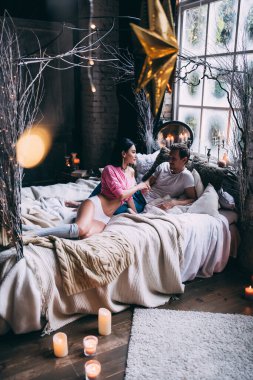 Mutlu genç çift, yataklarında rahat bir odada Noel süslemeleriyle  