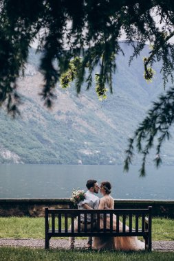 Düğün çifti gölün kenarında oturuyor.
