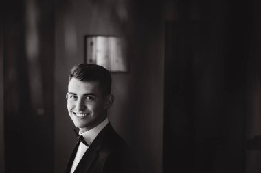 Yakışıklı genç damat portresi. Düğün gününde şık siyah takım elbise ve papyon takıyor.        
