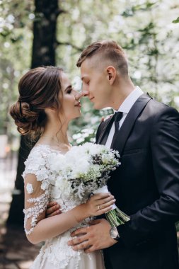 Güzel, mutlu, genç bir çift yeşil parkta birbirlerine poz veriyorlar.              