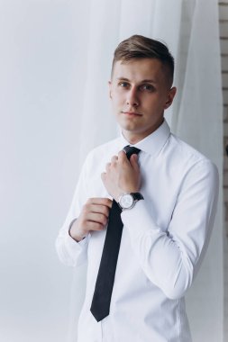 Beyaz gömlekli ve siyah kravatlı yakışıklı bir adamın portresi.