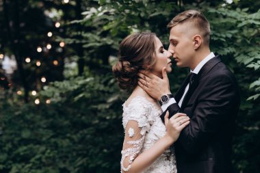 Güzel, mutlu, genç bir çift yeşil parkta birbirlerine poz veriyorlar.              