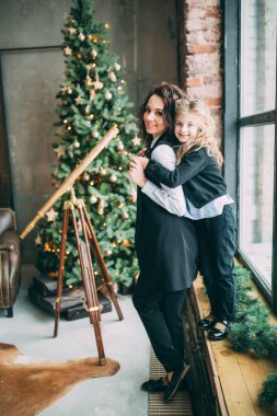 Anne ve kızı stüdyoda Noel ağacıyla poz veriyorlar.