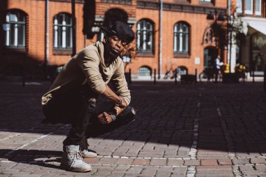 Afrika kökenli, güneş gözlüklü ve şapkalı bir Amerikalı şehirde poz veriyor.