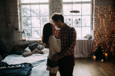 Güzel, mutlu, birbirine aşık genç bir çift sıcak bir odada kucaklaşıyorlar..                   