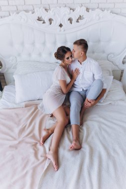 Birbirine aşık genç bir çiftin portresi. Yatakta sarılıyorlar.                