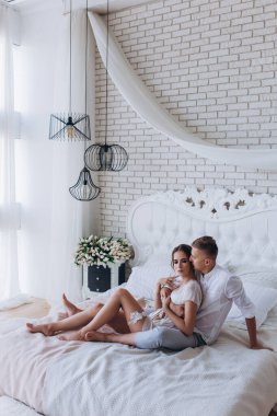 Birbirine aşık genç bir çiftin portresi. Yatakta sarılıyorlar.                