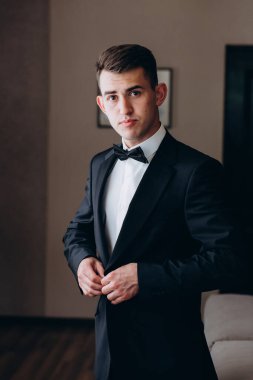 Yakışıklı genç damat portresi. Düğün gününde şık siyah takım elbise ve papyon takıyor.        