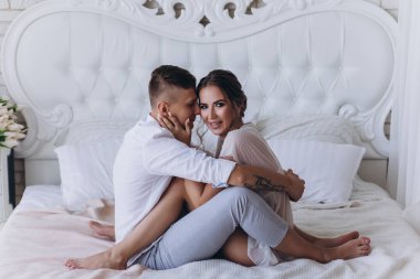 Birbirine aşık genç bir çiftin portresi. Yatakta sarılıyorlar.                