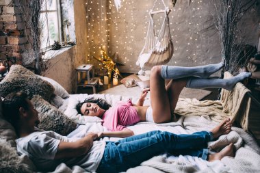 Genç, güzel bir kadın ve yakışıklı bir adam stüdyoda yatakta yatıyor. 