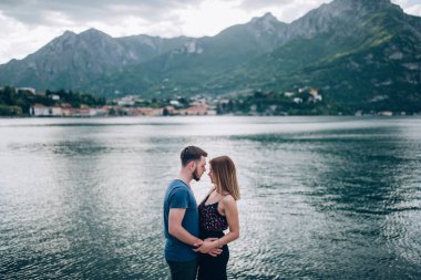 Genç çift, arka planda, dağlarda ve manzaralı gölde sarılıyor. 