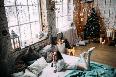 Güzel, genç, esmer bir kadın, rahat bir şekilde yatakta uzanıyor.                       