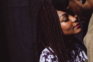 Genç ve güzel Afrikalı Amerikalı çift sarılıp öpüşüyor.