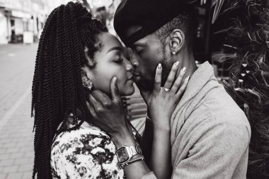 Afrikalı çift sokakta öpüşüyor ve sarılıyor.