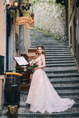 Güzel gelin elinde buketle merdivenlerde poz veriyor.     