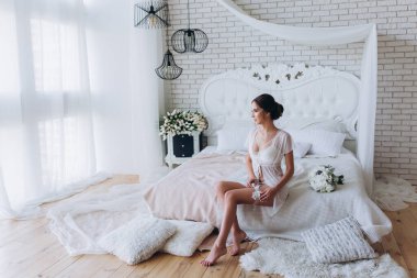 Beyaz dantelli iç çamaşırlı güzel bir kadın ve sabah yatak odasında bir buket düğün çiçeği.              